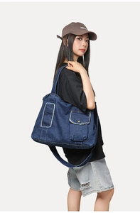 Détail d'un sac cabas en jean bleu foncé avec bords effilochés et grande boucle en métal