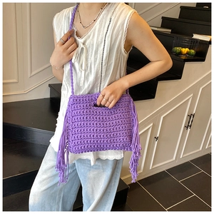 Detail view of purple knit crossbody bag with long fringes and woven shoulder strap