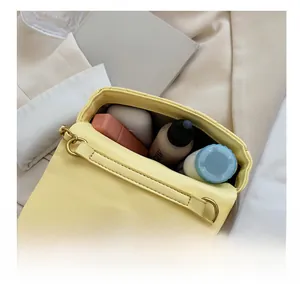 Interne capaciteit van lichtgele gewatteerde crossbodytas met lippenstift en foundation