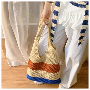 Detail of color-block woven tote bag with wide integrated handle and beach style texture