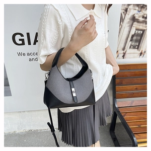 Détail d'un sac demi-lune chic en cuir noir, tissu gris et boucle en métal argenté