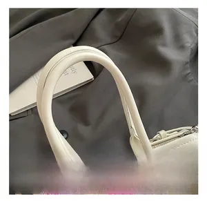 Détail du sac à main en cuir blanc avec bordure à carreaux roses et boucle argentée