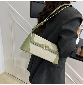 Detail of contrast canvas shoulder bag showing green PU trim and gold twist-lock closure