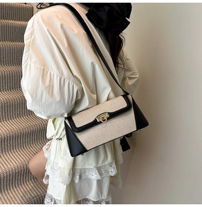 Detailed view of bicolor shoulder bag with vintage gold buckle on textured fabric