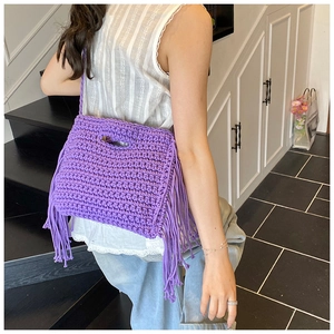 Close-up of hand-crocheted bright purple shoulder bag featuring long fringe tassels