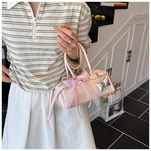 Détail du sac à main en cuir verni rose avec nœud en dentelle et pendentif papillon