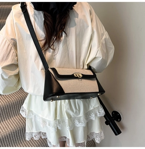 Detail of contrast stitching and gold metal feet on woven leather shoulder bag