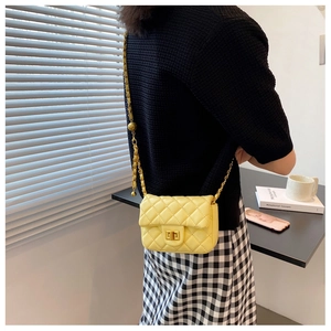 Detail van gele gewatteerde tas met goudkleurige sluiting en verstelbare ketting op model