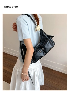 Detailansicht einer schwarzen Modeschultertasche mit silbernen Reißverschlüssen und Taschen