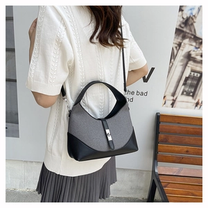 Détail du sac hobo bicolore en tissu gris avec finitions en cuir noir et boucle argent