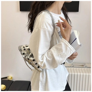 Detail of silver metallic punk bucket bag featuring large eyelets and elegant pearl charm