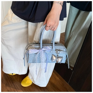 Détail du sac à main bleu clair texturé avec breloque nœud argenté et rubans dentelle