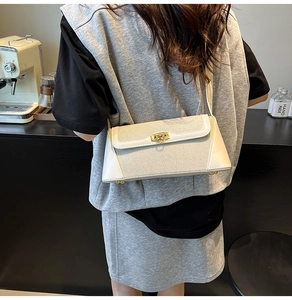 Side view of a cream shoulder bag featuring woven fabric textures and a gold lock