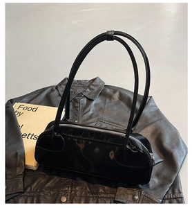 Détail du sac sous le bras en cuir noir brillant avec fermeture éclair argentée