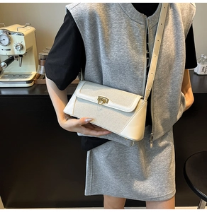 Detail view of the cream shoulder bag featuring premium texture and gold metal buckle on a model