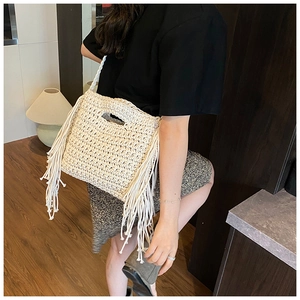 Detailed view of beige hand-woven crochet bag with stylish fringe and hollow handle design