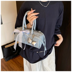 Détail du sac à main en tweed bleu clair avec nœud en dentelle et pendentif argenté