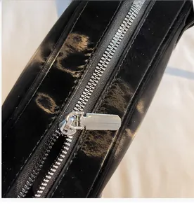 Détail du sac noir brillant montrant une fermeture éclair en métal argenté robuste