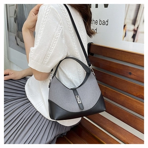Detail of grey dumpling bag showing metal lock and contrast leather shoulder strap