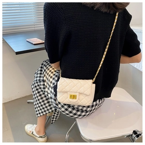 Detailweergave van witte gewatteerde tas met goudkleurige ketting en klassiek slotje