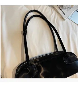 Détail du sac en cuir brillant noir avec fermeture éclair sur un tissu blanc