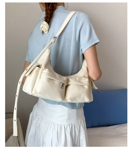 Detailansicht der cremefarbenen Lederschultertasche mit mehreren funktionalen Reißverschlüssen