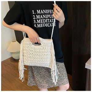 Detail of hand-woven cream knit bag featuring long fringe accents and textured grid pattern