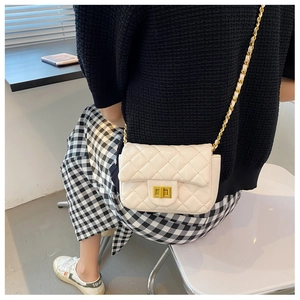 Detailweergave van een beige gewatteerde crossbodytas met gouden ketting bij een model