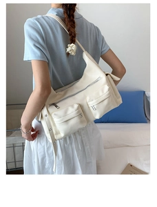Detail der cremeweißen Kunstleder-Tasche mit Multi-Taschen-Design und breitem Gurt
