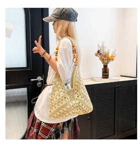 Detail of hollow-out beige crochet tote bag with decorative wooden beads on strap