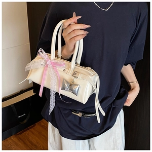 Détail du sac à main crème avec nœud en dentelle rose et pendentif en argent élégant