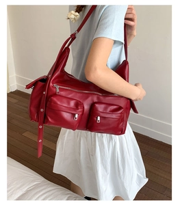 Detail of dark red leather tote bag with functional zip pockets and adjustable strap