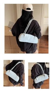 Détail du sac Boston en cuir bleu clair avec double fermeture éclair porté par un mannequin