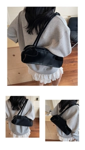 Détail d'un sac baguette noir brillant avec de longues et fines bandoulières élégantes