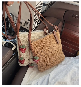 Detail of hand-woven crochet crossbody bags in cream and camel with strawberry charms