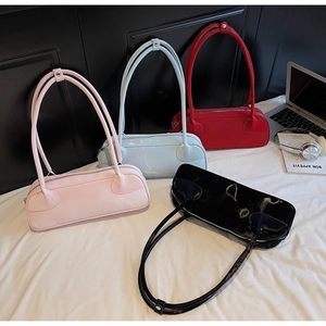 Détails de quatre sacs baguette en cuir verni brillant coloré sur un lit blanc