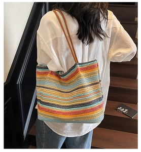 Close-up of a large colorful striped woven tote bag with brown leather shoulder straps