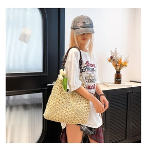 Detail of a large woven straw tote bag featuring decorative wooden bead handles for summer