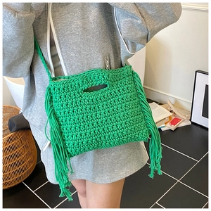 Detail of bright green woven handbag with long fringe tassels and crochet texture