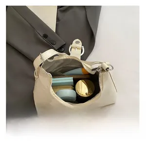 Interior view showing the large capacity of a beige leather underarm bag with daily items