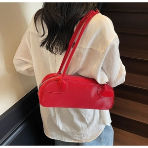Macro shot of red glossy Boston bag with silver zipper on model's shoulder