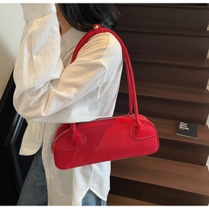 Minimalist red leather long bowling bag held by model on wooden stairs