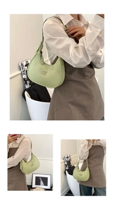 Detail of mint green crescent bag with lychee grain texture and metal logo plaque