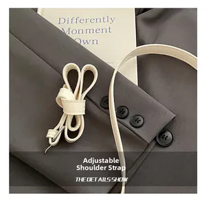 Close-up of a white leather adjustable shoulder strap with a silver metal buckle