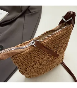 Close-up of smooth metal zipper and brown leather pull on woven crossbody bucket bag