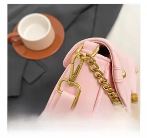 Detail view of pink quilted handbag with golden chain strap and metallic hooks