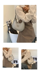 Detail view of light grey hobo bag showing litchi grain texture and square logo plaque