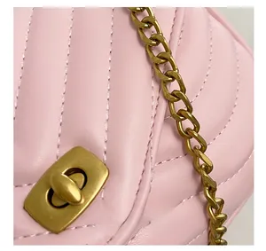 Detail of pink quilted shoulder bag featuring gold twist lock and metal chain strap