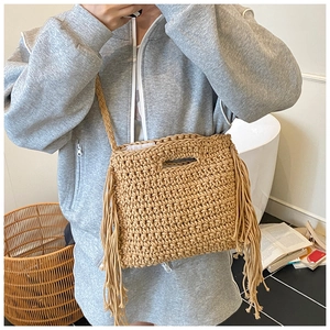 Close-up of bohemian hand-woven straw bag with long fringe tassels and texture details