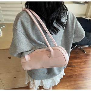 Sac baguette rose pâle à double bandoulière porté sur un sweat-shirt gris